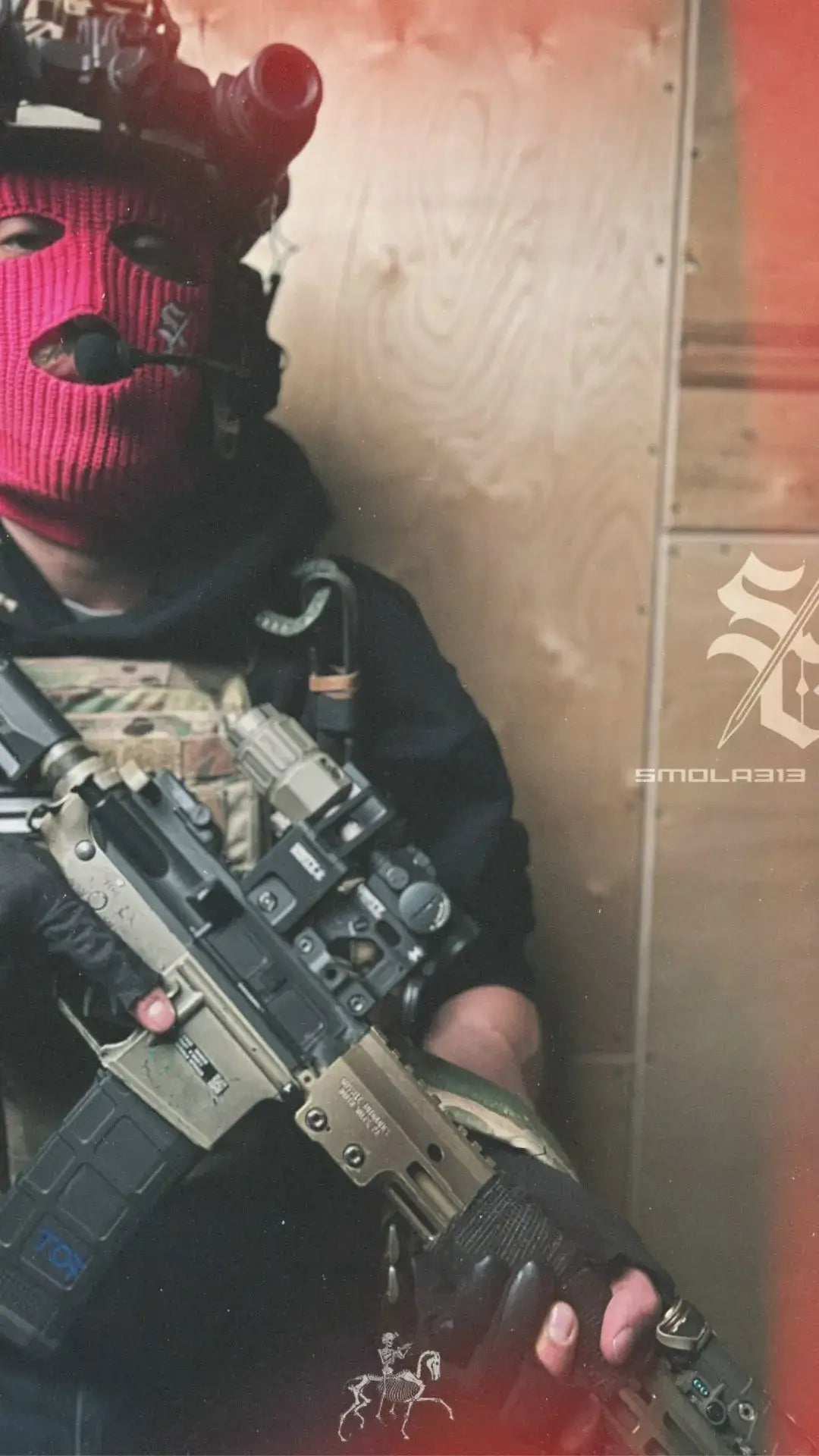 Person wearing a pink mask and holding a rifle against a blurred background