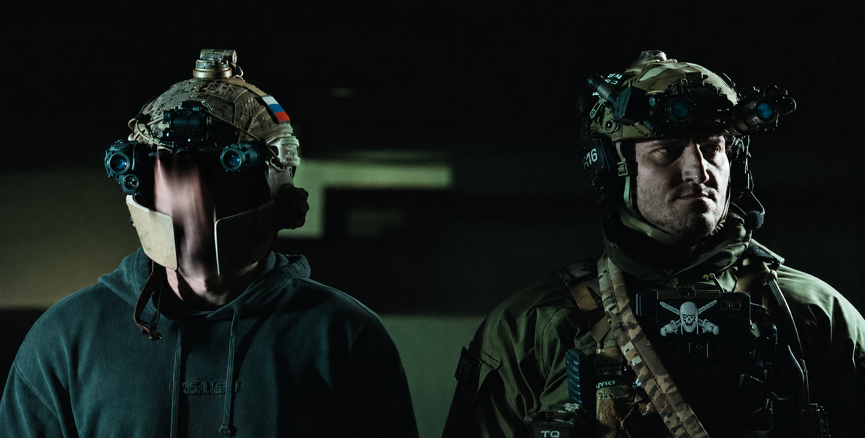 Two individuals in tactical gear with helmets and masks in a dark setting